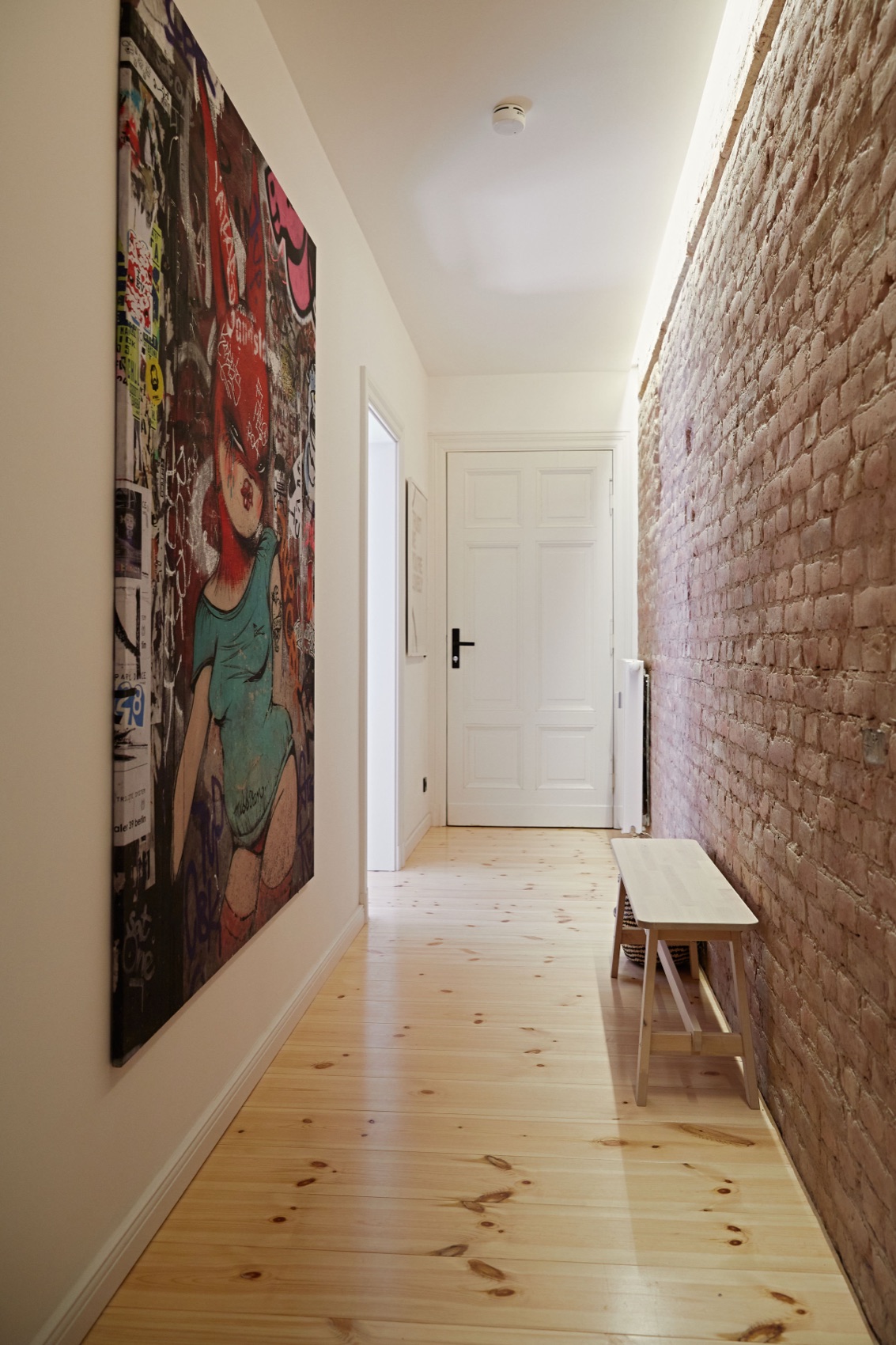 Hallway with exposed brick wall and art, connecting the rooms